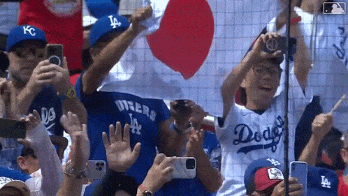 a crowd of people are watching a baseball game and taking pictures with their phones .