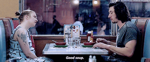 a man and a woman are sitting at a diner table eating soup and the man says good soup