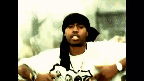 a man wearing a bandana and a white shirt is standing in front of a crowd of people .
