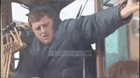 a man in a blue jacket is sitting in a vehicle with his arms outstretched