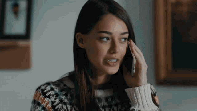 a woman in a sweater is talking on a cellphone