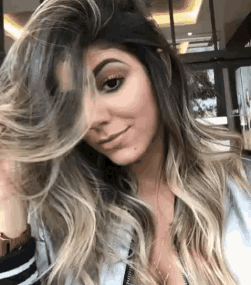 a woman with long hair is smiling and holding her hair