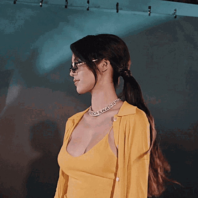a woman wearing a yellow top and a necklace with rhinestones