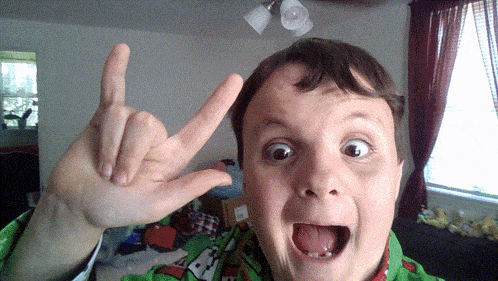 a young boy making a devil horns sign with his fingers