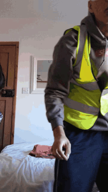 a man wearing a yellow vest is standing in a room