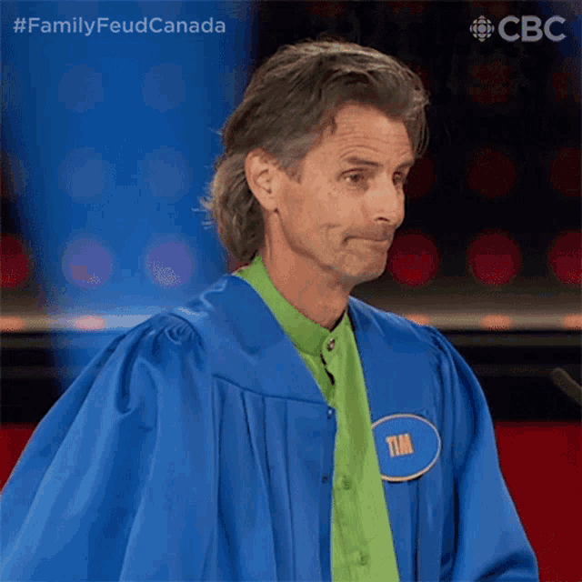 a man in a blue gown and green shirt has a name tag that says tim on it