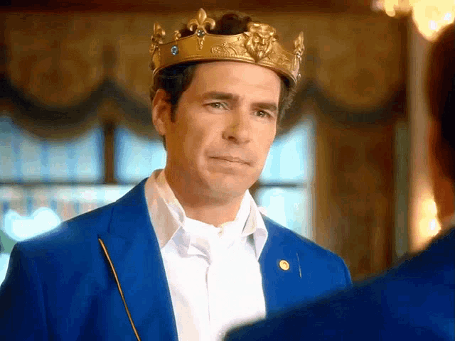 a man in a blue suit is wearing a gold crown on his head