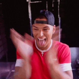 a man wearing a red shirt and a black hat is making a funny face with his tongue out