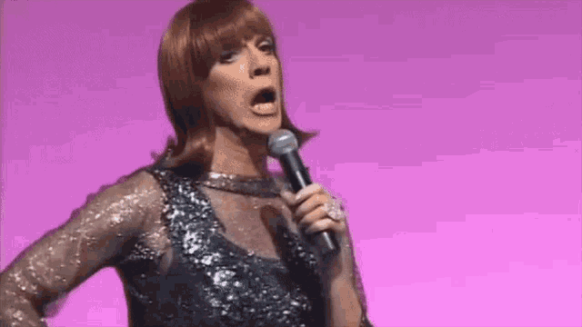 a woman in a sequined dress is singing into a microphone .