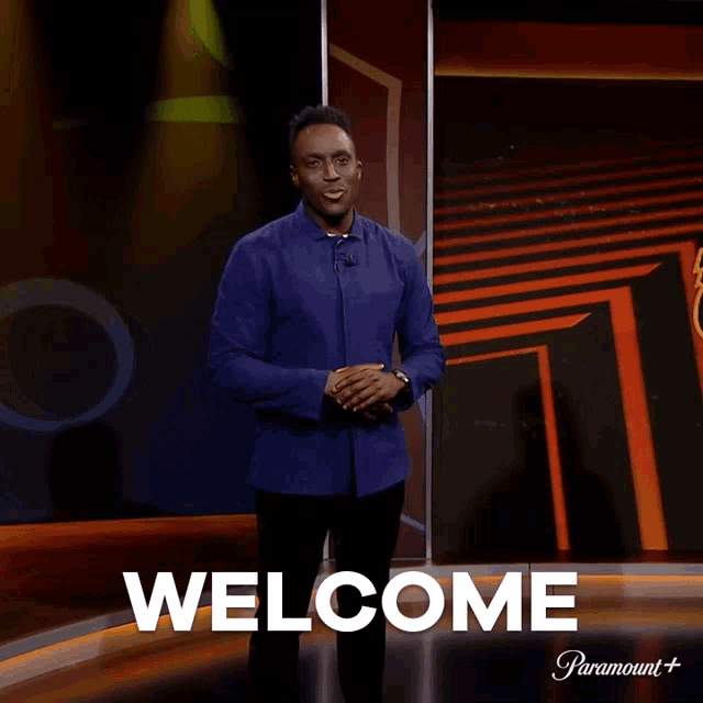 a man is standing in front of a screen that says welcome