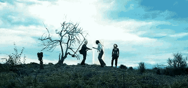 a group of people are standing on top of a grassy hill .