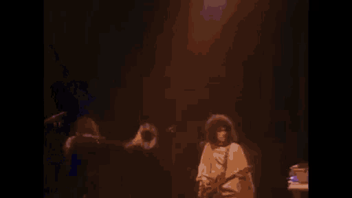 a man is playing a trumpet on a stage while another man plays a guitar .