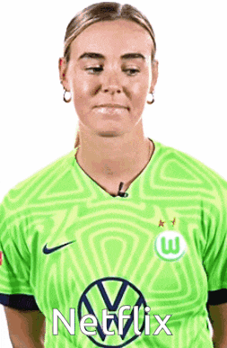 a woman wearing a green netflix shirt is making a funny face .