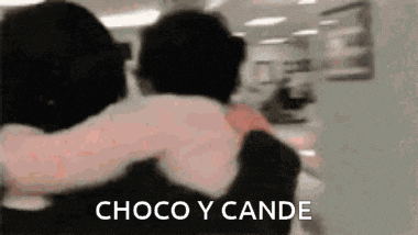a couple of people hugging each other in a room with the words choco y cande on the bottom .
