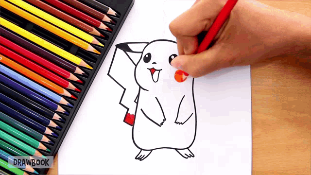 a person is drawing a pikachu on a piece of paper with drawbook pencils in the background
