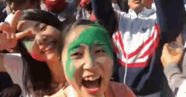 a woman with green paint on her face is surrounded by other people