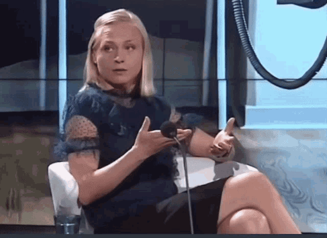 a woman sitting in front of a microphone with her legs crossed