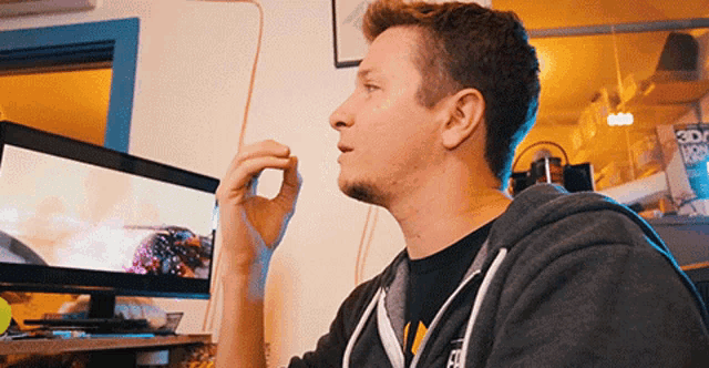 a man in a hoodie looks at a computer screen with the word 3d on it