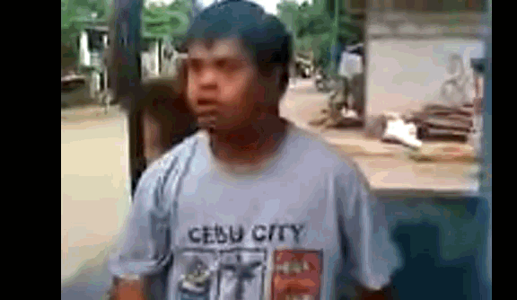 a man wearing a cebu city t-shirt is standing on a street .
