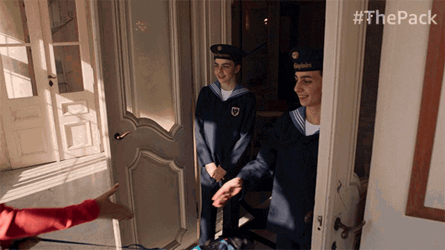 two men in uniform are standing in a doorway with #thepack written on the bottom right