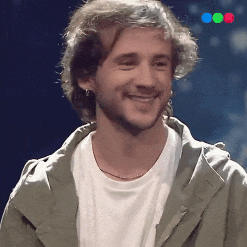 a man in a white shirt and a green jacket smiles