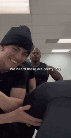 a man wearing a beanie is holding another man 's butt while another man looks on .