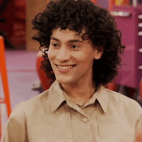 a woman with curly hair is smiling and wearing a tan jacket