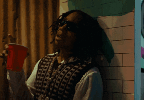 a man is drinking from a red cup that says supreme on it