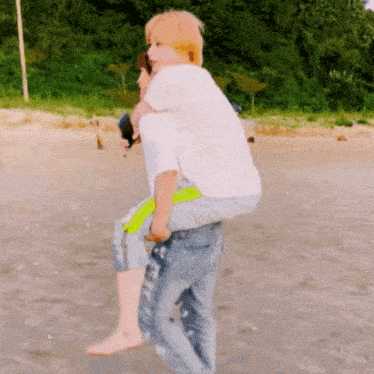 a person is carrying another person on their back on the beach