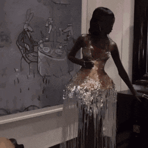 a woman in a dress is standing in front of a painting of a rabbit