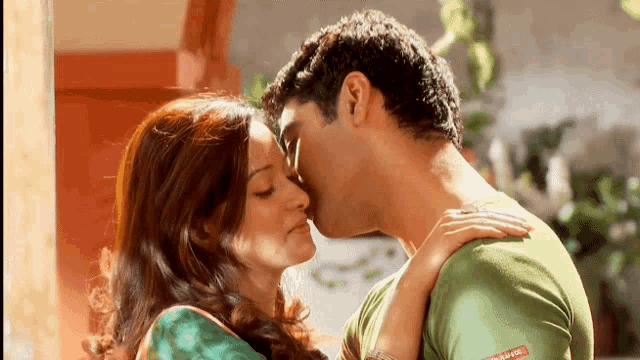 a man and a woman are kissing with the man wearing a green shirt that says ' levis ' on it