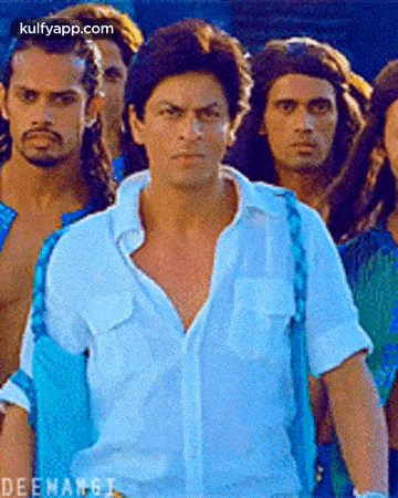 a man in a blue shirt is standing in front of a group of men .