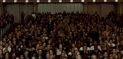 a large crowd of people are sitting in a large auditorium watching a show