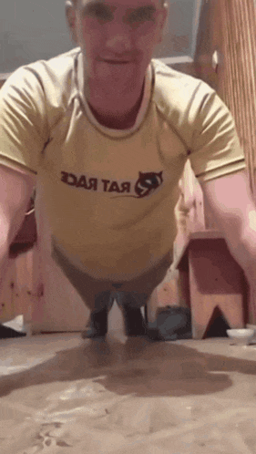 a man is doing push ups in a yellow shirt that says ' daa taa ' on it