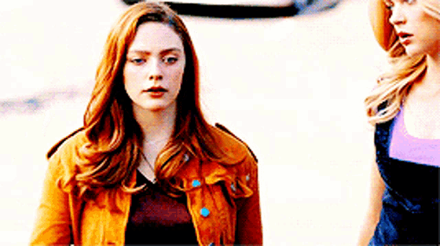 a woman with red hair is standing next to another woman