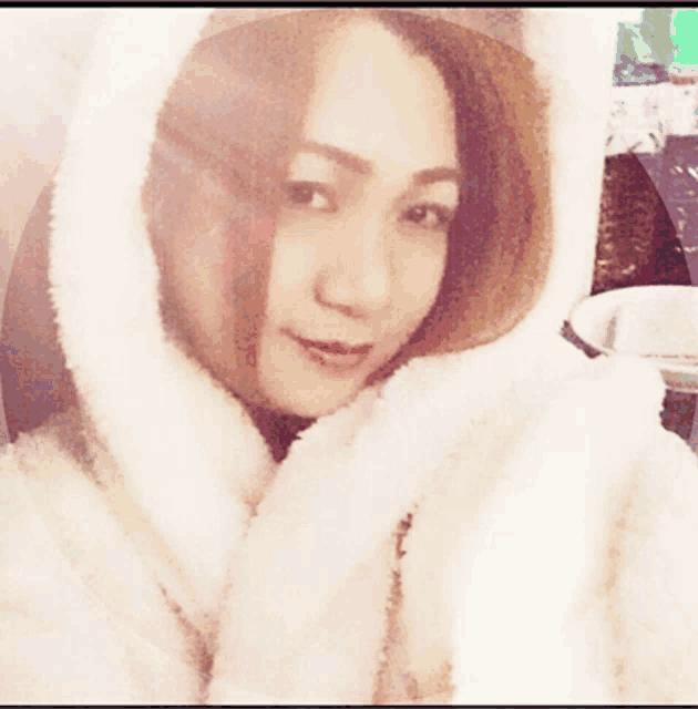 a woman is wearing a white fur coat with a cat ear hood