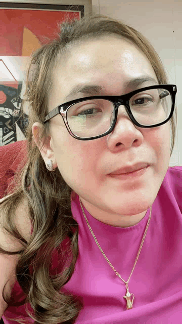 a woman wearing glasses and a necklace is smiling
