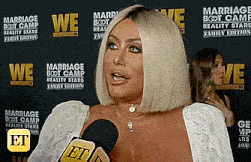 a woman speaking into a microphone in front of a wall that says marriage boot camp reality stars