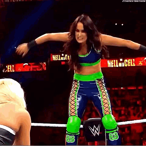 a female wrestler is standing in a wrestling ring with her arms outstretched .