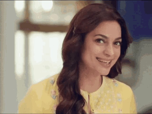 a woman wearing a yellow dress is smiling and looking at the camera