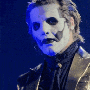 a close up of a man with white face paint and a black suit