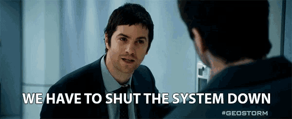 a man in a suit and tie is talking to another man with the words we have to shut the system down below him