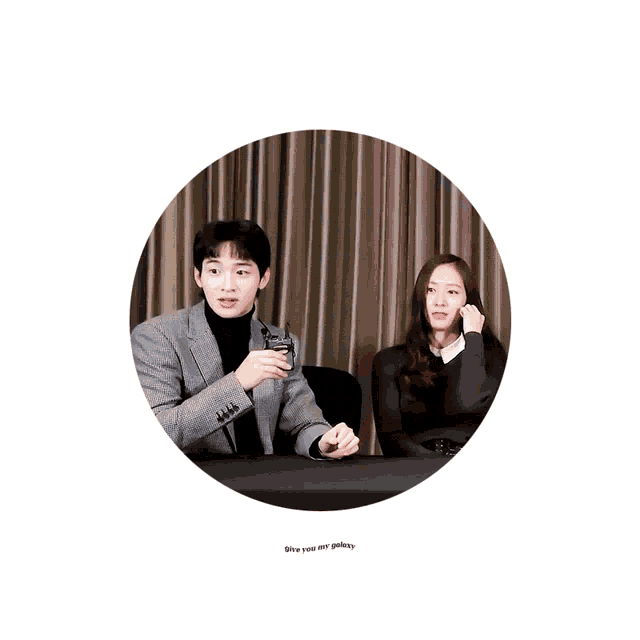 a man and a woman are sitting at a table with a sign that says give you my galaxy