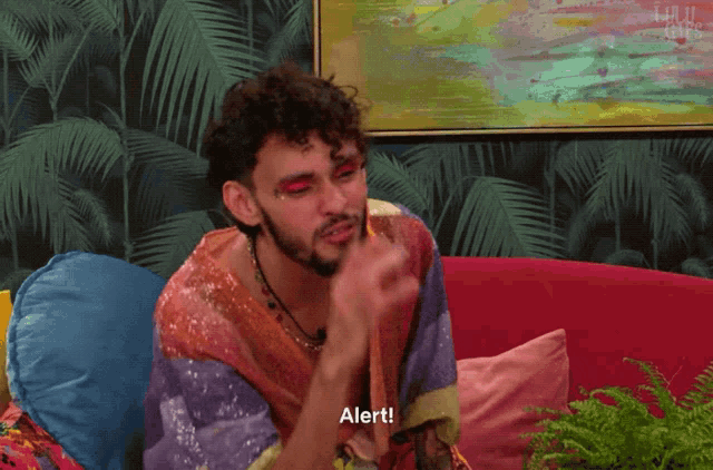 a man sitting on a couch with alert written on the bottom of his face