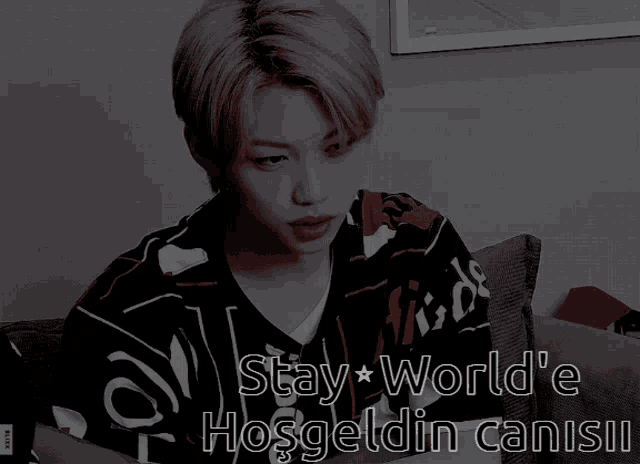 a man is sitting on a couch wearing a shirt that says stay world 'e hoşgeldin canisii