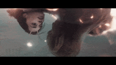 a woman is upside down in the water looking at a man 's face