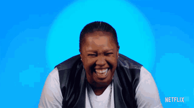 a woman is laughing in front of a blue background with netflix written on the bottom