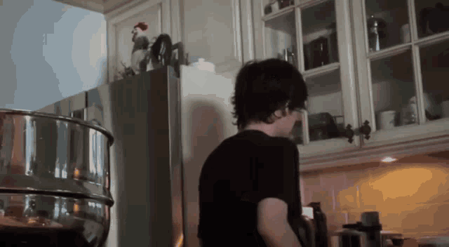 a man in a black shirt is in a kitchen