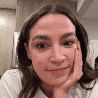 a close up of a woman 's face with her hand resting on her chin