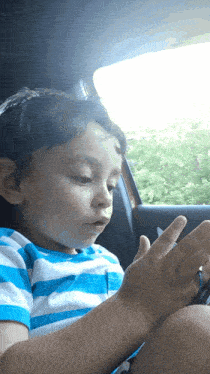 a young boy is sitting in the back seat of a car looking out the window